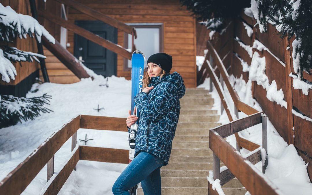 A girl skier standing by a log cabin